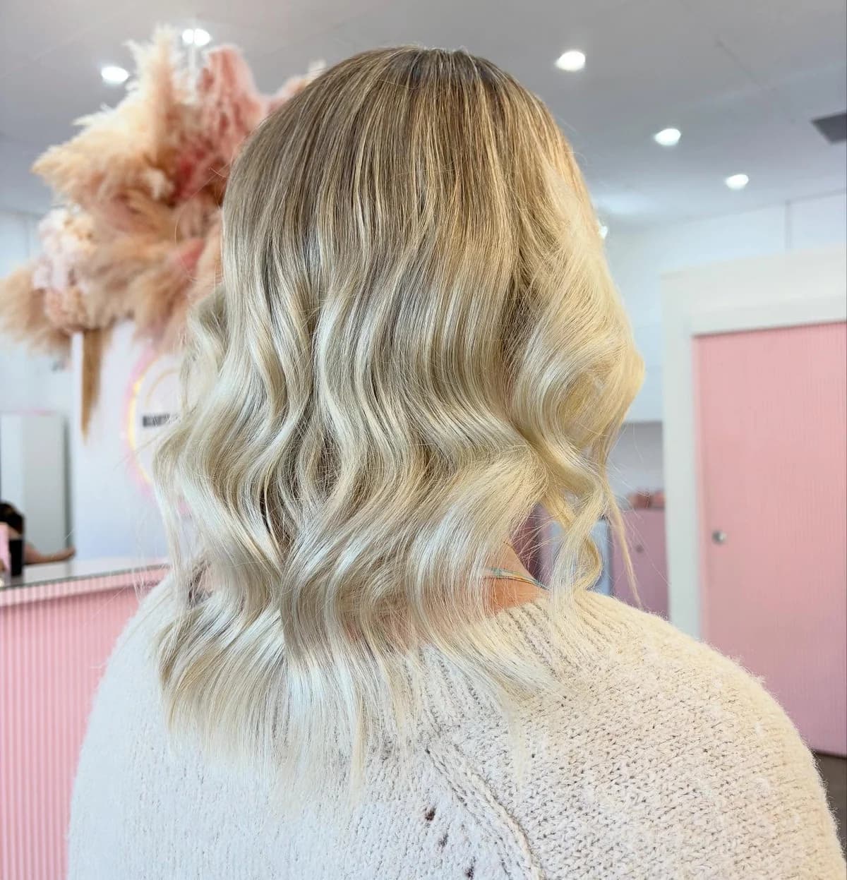 Creamy blonde waves with natural root dimension, viewed from the back