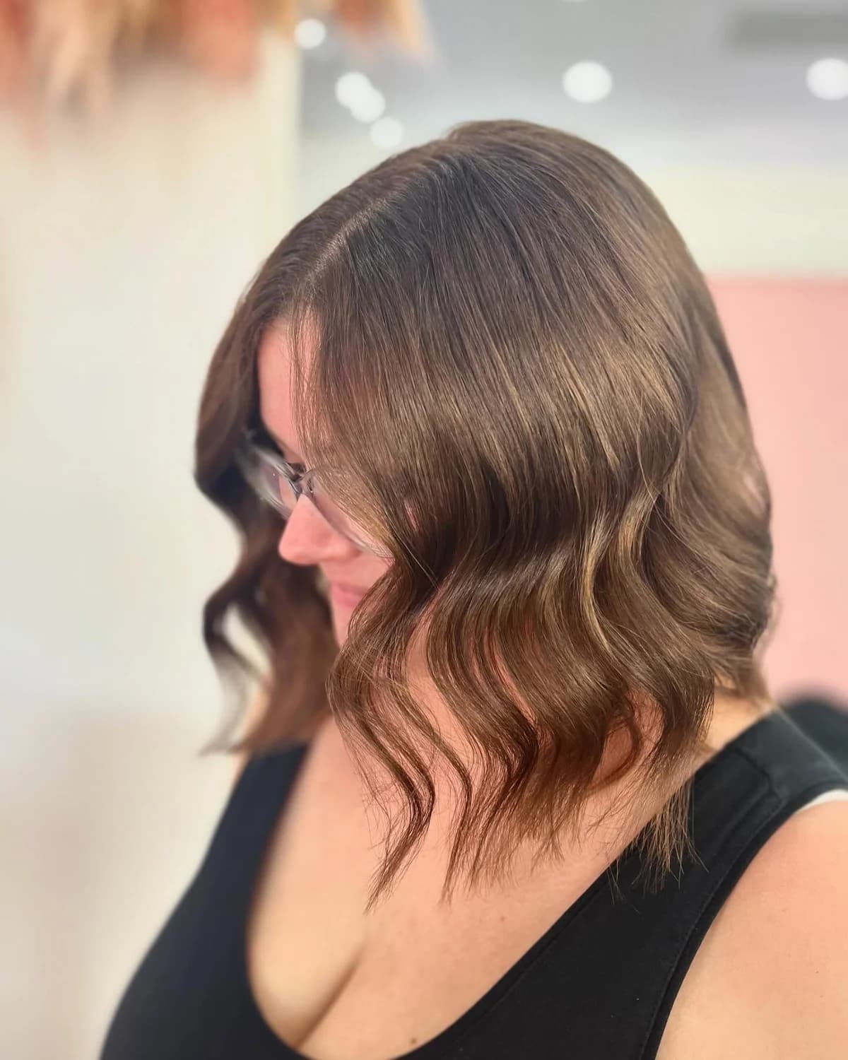 Glossy brunette bob with soft waves and warm highlights